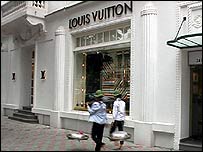 Hai người dân đi ngang qua cửa hàng của Louis Vuitton