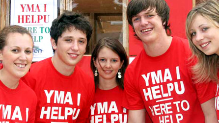 Pump o bobl ifainc yn wisgo crysau t goch 'Yma i helpu'