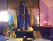 Soft lighting, mats and decorations surround an altar and statue of the Goddess