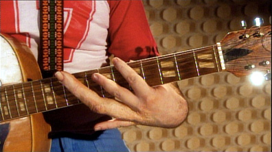 Hand with double-length finger playing guitar