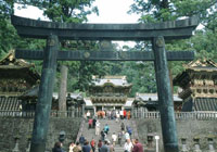 Torii arch and wide staircase full of people climbing up to the Tosho Gu shrine, a collection of buildings with gold-painted roofs