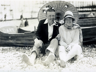 Couple sitting on beach holding parasol