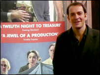James standing by the Twelfth Night poster