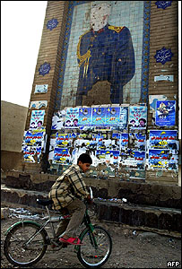 Menino em frente à propaganda política no Iraque