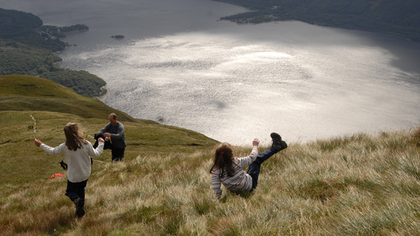 Girls sliding down grass