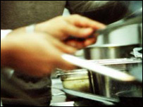 Elinde yemek çubukları olan ve yemek pişiren biri