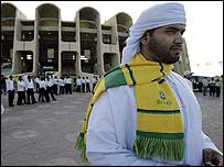 Torcedor local veste cachecol do Brasil em frente ao estádio de Abu Dhabi