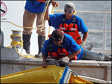 Trabajadores colocan barreras de contención de crudo en el agua