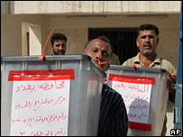 Funcionários carregam urnas do referendo no Iraque 