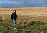 Woman walking along path beside crops