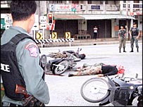 मारे गए हमलावरों को देखते थाई सुरक्षाकर्मी