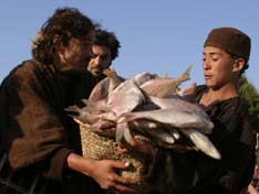 A boy about to spill a basket of fish while handing it to Jesus