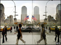 Espelho reflete imagem de pedestres diante de bandeira a meio pau no Ground Zero