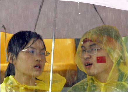 Chinese archery fans attempt to shelter from the torrential rain