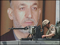 يک سرباز خارجی در کنار عکس حامد کرزی در کابل