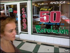 Một phụ nữ đi ngang qua quán cafe có dòng chữ '50 năm cách mạng Cuba sống mãi'