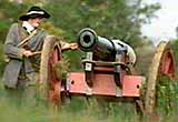 An artillery soldier in period costume about to fire a cannon in a English Civil War battle re-enactment