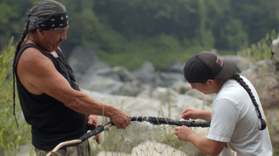 Two people building a fishing net.