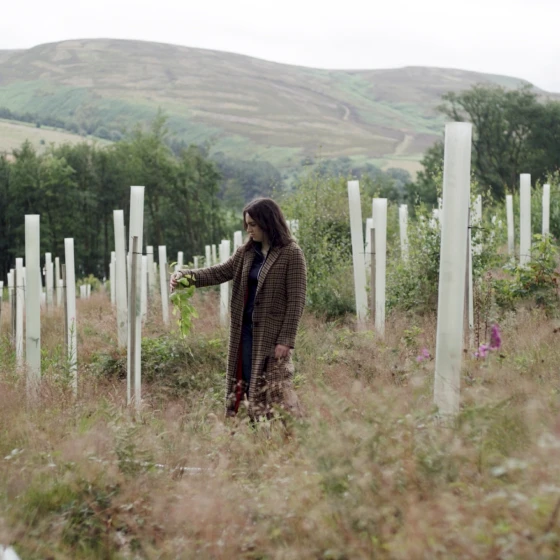 A woman standing in a farm with growing plants around her.